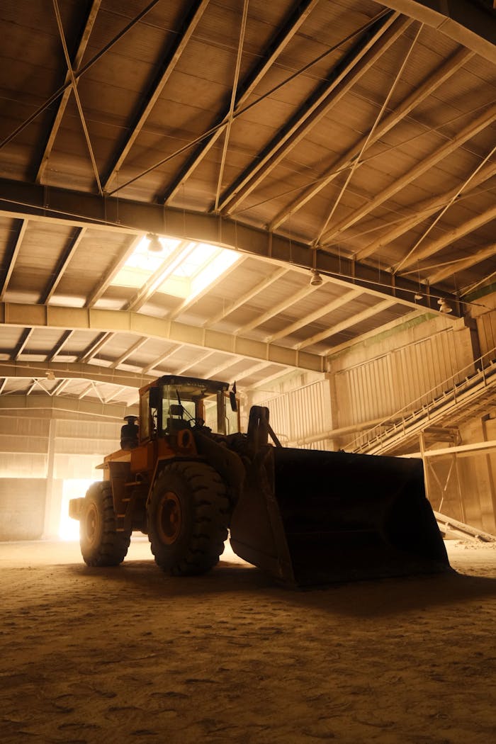 A bulldozer parked inside a large industrial warehouse, bathed in warm light.
